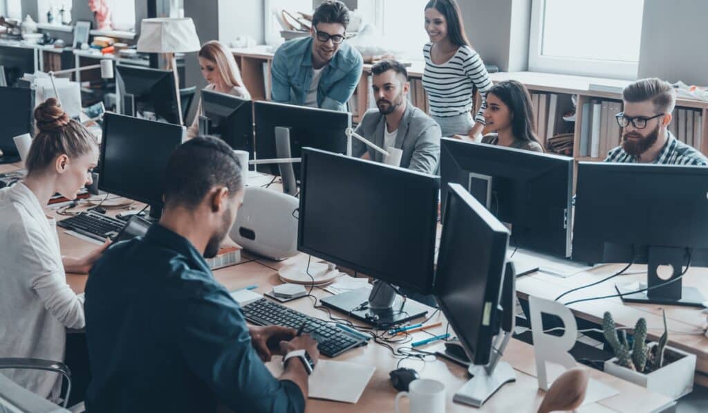 a group of people sitting at a table with computers