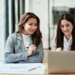 a couple of women looking at a laptop