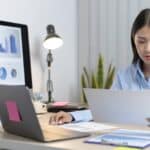 a woman sitting at a desk looking at a paper