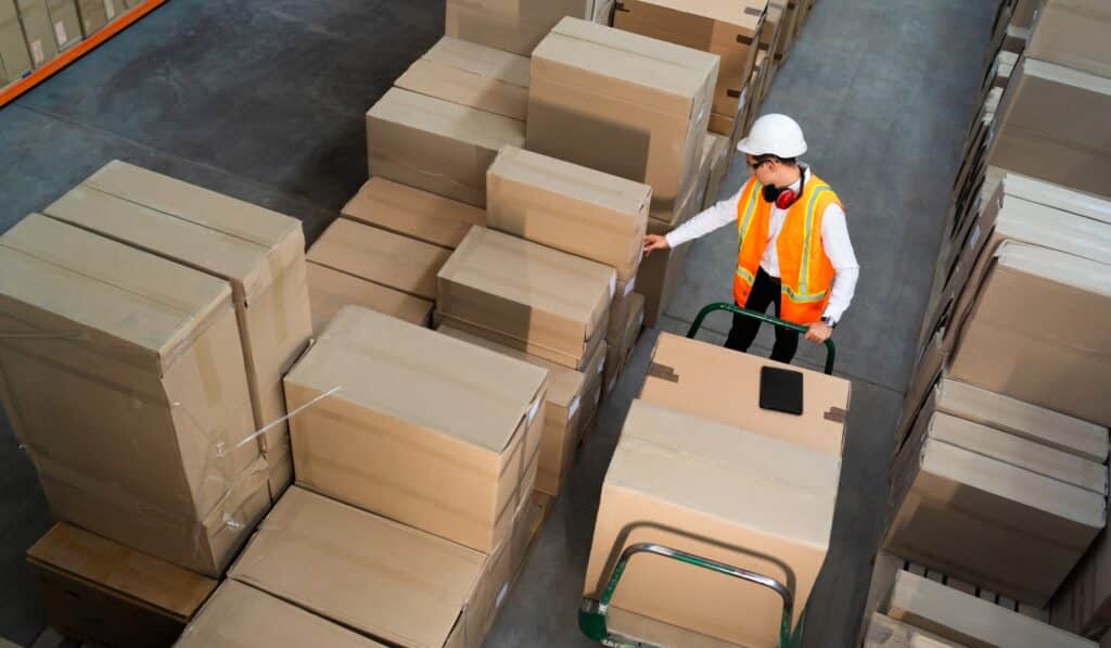 a man in a vest pushing a cart with boxes